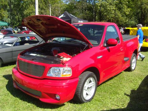 2007 Ford Mustang - A red pickup truck is displayed with its hood open at an outdoor event.