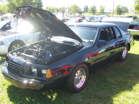 2007 Ford Mustang - A black coupe with its hood open, revealing the engine bay, sits on display at an outdoor event.
