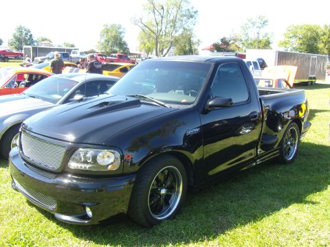2007 Ford Mustang - A black Ford F-150 Lightning pickup truck is parked on grass at an outdoor event.
