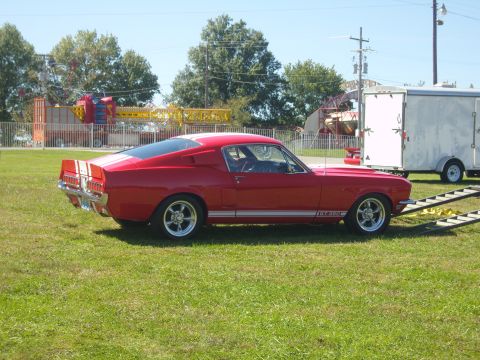 2007 Ford Mustang - Classic red Ford Mustang GT 350 parked on grass with a trailer nearby.