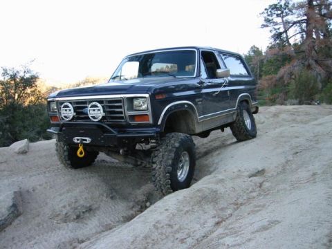 1985 Ford Bronco - This modified Ford Bronco is navigating a challenging off-road trail.
