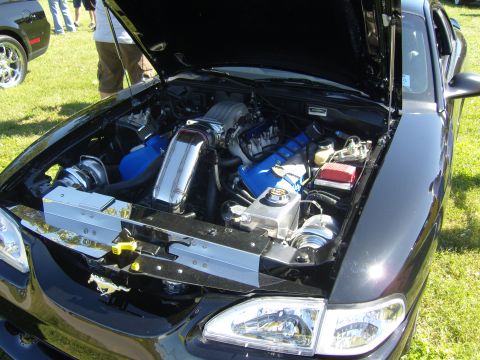2007 Ford Mustang - The engine bay of a black Ford Mustang is open, showing a modified engine with blue components and chrome accents.