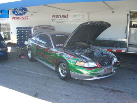 2007 Ford Mustang - A customized Ford Mustang with flame graphics and an open hood sits under a tent next to a trailer.