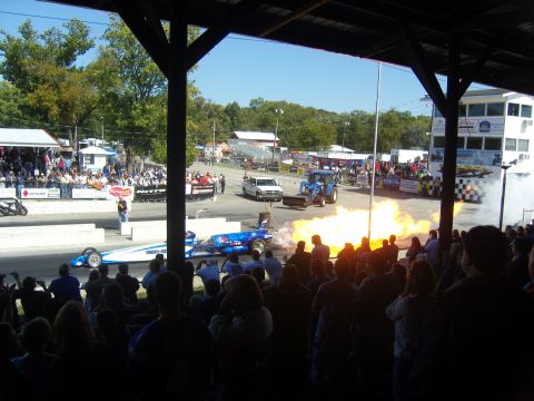 2007 Ford Mustang - Spectators watch a drag race event a dragster and a tractor with a large flame effect.