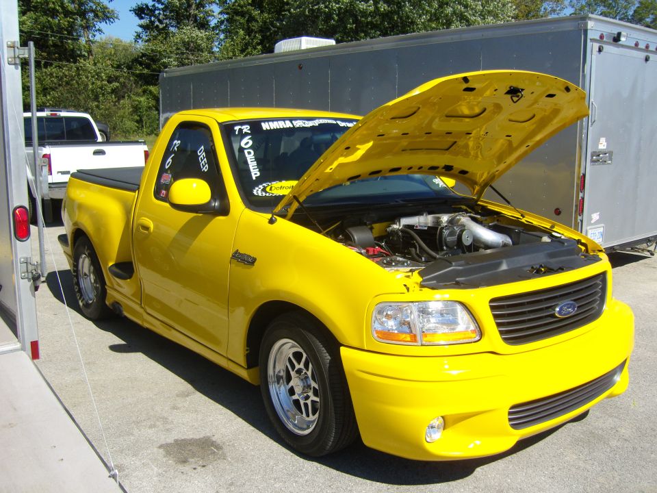 Yellow 2007 Ford F-150 Lightning pickup truck, hood open, showing engine and supercharger