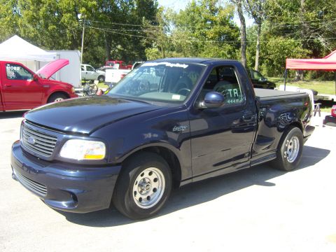 2007 Ford Mustang - Dark blue Ford F-150 Lightning pickup truck with racing decals on the windshield.