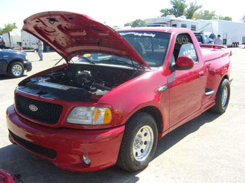 2007 Ford Mustang - A red Ford F-150 SVT Lightning pickup truck is parked with its hood open, revealing the engine bay.