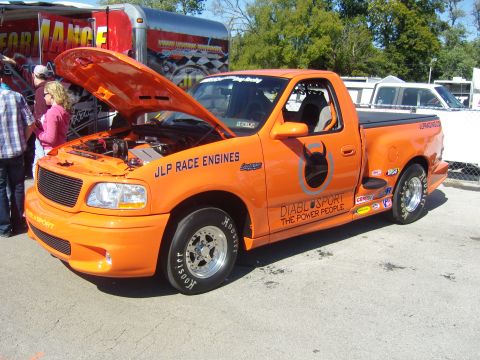 2007 Ford Mustang - This orange 2007 Ford F-150 Lightning pickup truck features custom graphics and an open hood revealing its engine.