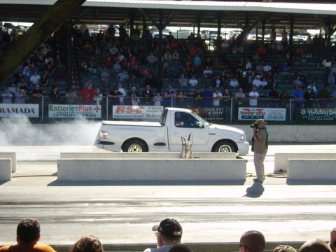 2007 Ford Mustang - White pickup truck performs a burnout at a drag racing event.