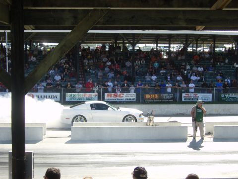 2007 Ford Mustang - A white Ford Mustang creates smoke during a burnout at a drag racing event.