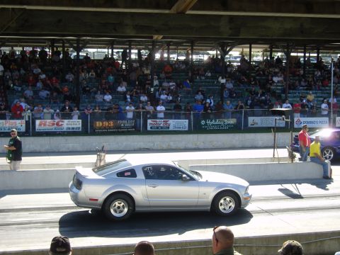2007 Ford Mustang - A silver Ford Mustang is positioned on a drag strip, with spectators in the background stands.