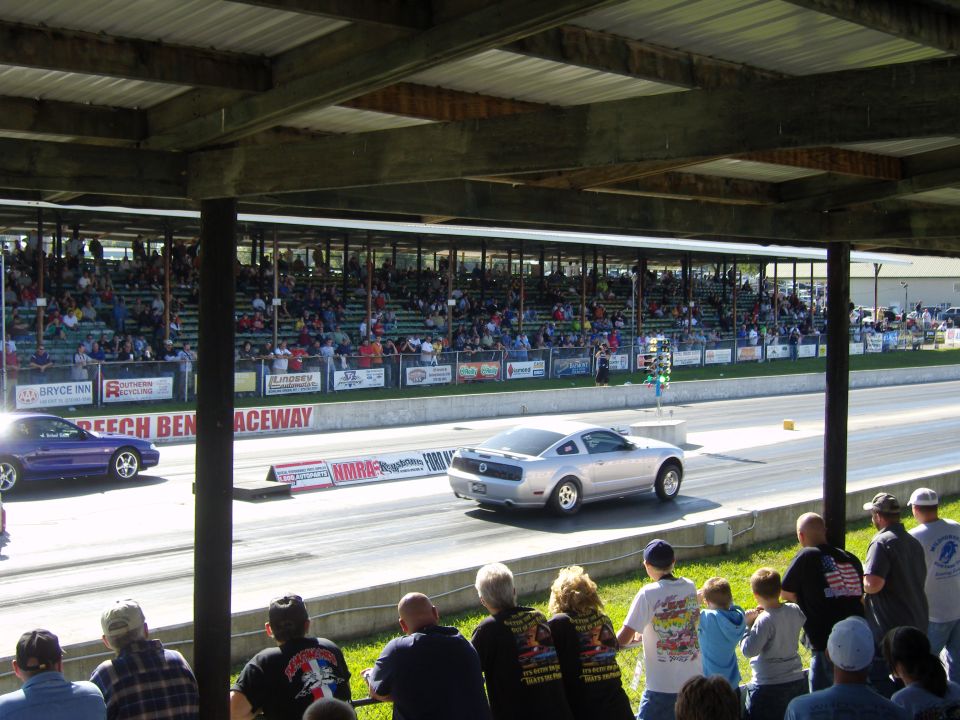 Silver 2007 Ford Mustang racing on a track, rear view