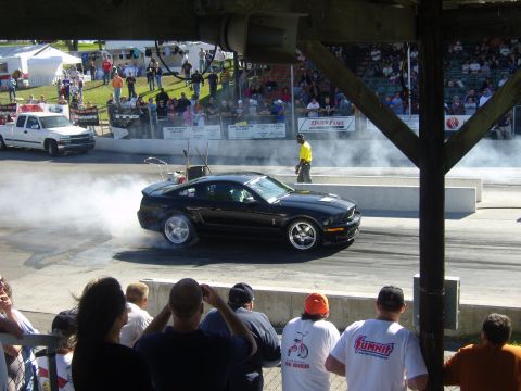 2007 Ford Mustang - A black 2007 Ford Mustang performs a burnout at a drag racing event.