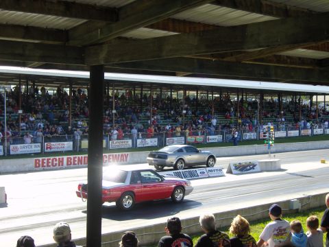 2007 Ford Mustang - Two Mustangs race down the Beech Bend Raceway, with spectators in the stands.