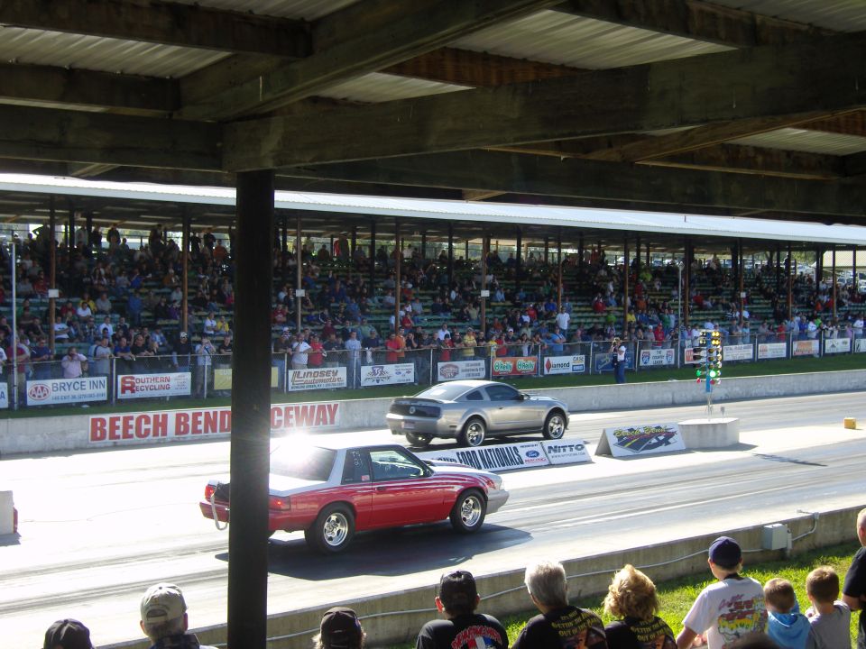 Silver Ford Mustang on a drag strip, side view. Red Mustang in foreground