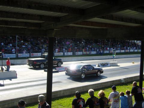 2007 Ford Mustang - Cars compete on a drag strip during a race event with a crowd watching from the stands.