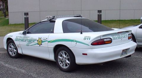 2000 Ford Crown Victoria - This white police car displays "Kittitas County Sheriff" and "Dial 911" graphics along with green racing stripes.