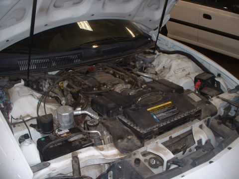 2000 Ford Crown Victoria - The engine bay of a white car is shown with the hood open.