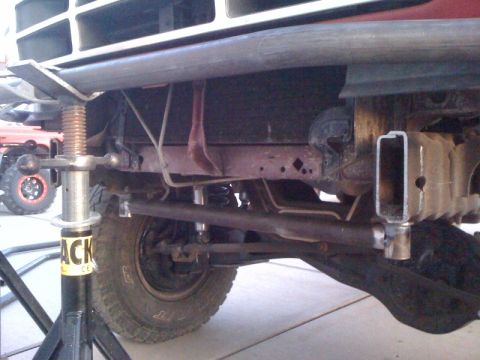 1989 Ford Bronco - Close-up of the front suspension and frame of a 1989 Ford Bronco, supported by a jack stand.
