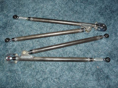 1994 Ford F-150 - Four fabricated bare-steel suspension link bars laid out on green carpet, each with heim-joint rod ends and threaded adapters at both ends…