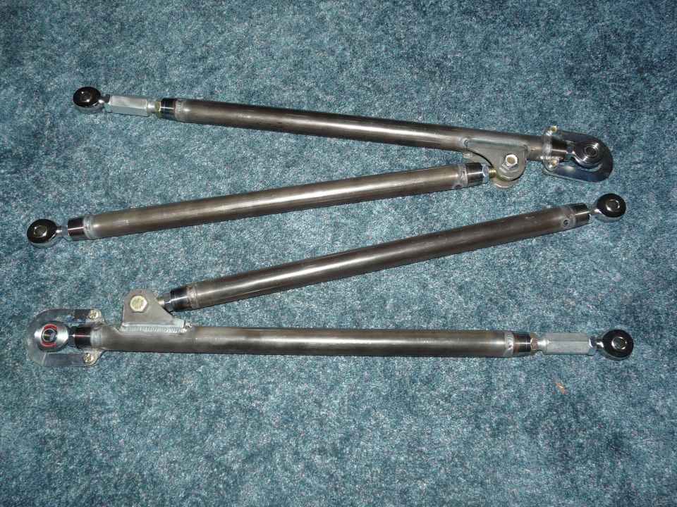 Four bare-steel four-link suspension bars with heim joints laid out on carpet