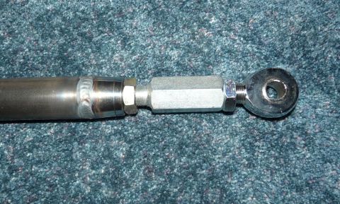 1994 Ford F-150 - Close-up of an adjustable tie rod end assembly, a hex adjustment sleeve and a threaded stud, set against a carpeted background.