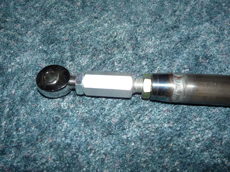 Close-up of a heim joint rod end and jam nut threaded into a welded steel suspension link