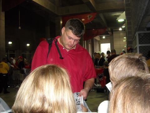 1979 Ford F-150 - A man signs autographs for fans, with Atlanta Falcons banners visible in the background.