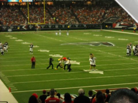 1979 Ford F-150 - A football game is underway with players and mascots on the field, and spectators in the stands.