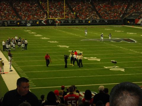 1979 Ford F-150 - A football game is underway with players and officials on the field and a crowd in the stands.
