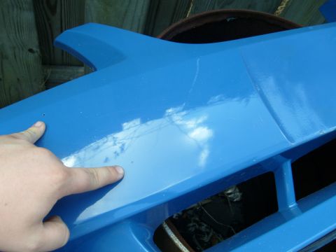 1992 Ford Bronco - Close-up of a blue car fender showing damage and a finger pointing to scratches.