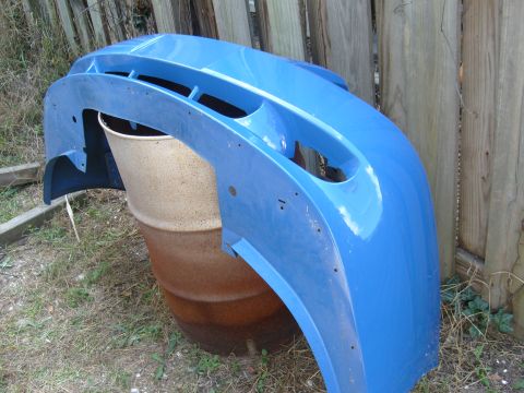 1992 Ford Bronco - A blue plastic bumper is shown leaning against a barrel outdoors.
