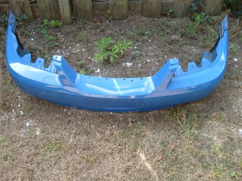 1992 Ford Bronco - A blue car bumper is shown from the front, resting on dry grass and dirt.