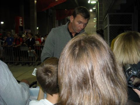 1979 Ford F-150 - A man in a grey sweater signs autographs for fans gathered behind a metal barrier.