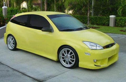 1999 Ford Taurus - A yellow hatchback car is parked on a paved surface, viewed from the front three-quarter angle.