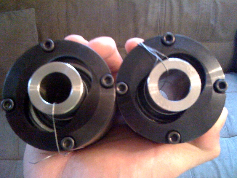 two black metal automotive parts with silver rings held in a hand