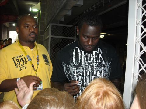 1979 Ford F-150 - An event staff member stands by as a man signs autographs for a crowd of fans.