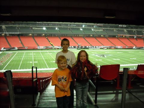 1979 Ford F-150 - Three children pose for a photo in the stands of a football stadium, with the field visible in the background.