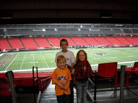 1979 Ford F-150 - Three children pose for a photo in a stadium, with the football field visible behind them.