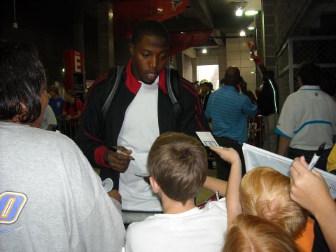 1979 Ford F-150 - A man signs autographs for a group of children at an indoor event.