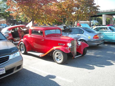 1979 Ford F-150 - A red coupe hot rod is parked among other vehicles at an outdoor event.