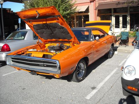 1979 Ford F-150 - A classic orange Dodge Charger is displayed with its hood open at a car show.