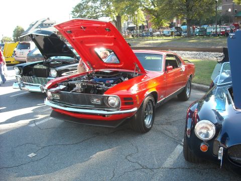 1979 Ford F-150 - A red 1970s muscle car is displayed with its hood open at a car show, revealing the engine bay.