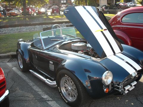 1979 Ford F-150 - A dark blue convertible sports car with its hood open is parked next to a red car.