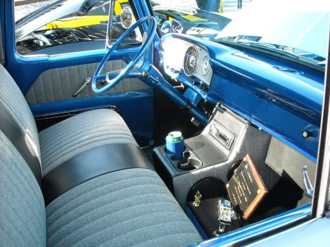 1979 Ford F-150 - Interior view of a blue truck, showing the dashboard, seats, and center console with a drink and awards.