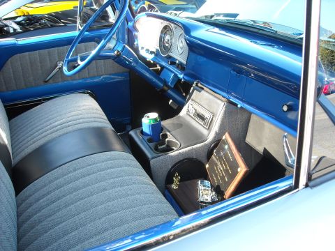 1979 Ford F-150 - The interior of a 1979 Ford F-150 shows off its blue dashboard, grey striped seats, and a center console with a radio and cup holder.