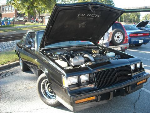 1979 Ford F-150 - A black 1987 Buick Regal Grand National is displayed with its hood open, revealing the engine and turbocharger details.