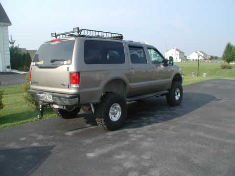 2000 Ford Excursion - This lifted 2000 Ford Excursion features a roof rack and is viewed from the rear 3/4 angle.