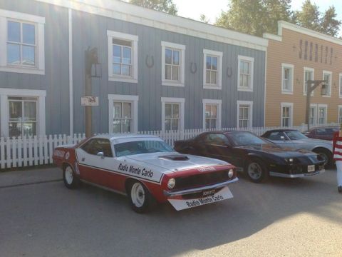 1991 Ford LTD Crown Victoria - A 1970 Plymouth Barracuda is parked in front of a building with other vehicles visible.