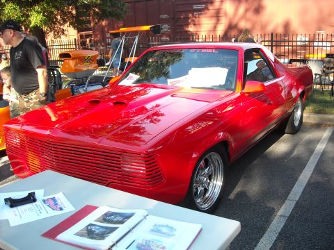 1979 Ford F-150 - A heavily modified red pickup truck is displayed at a car show, a unique front grille and custom hood.